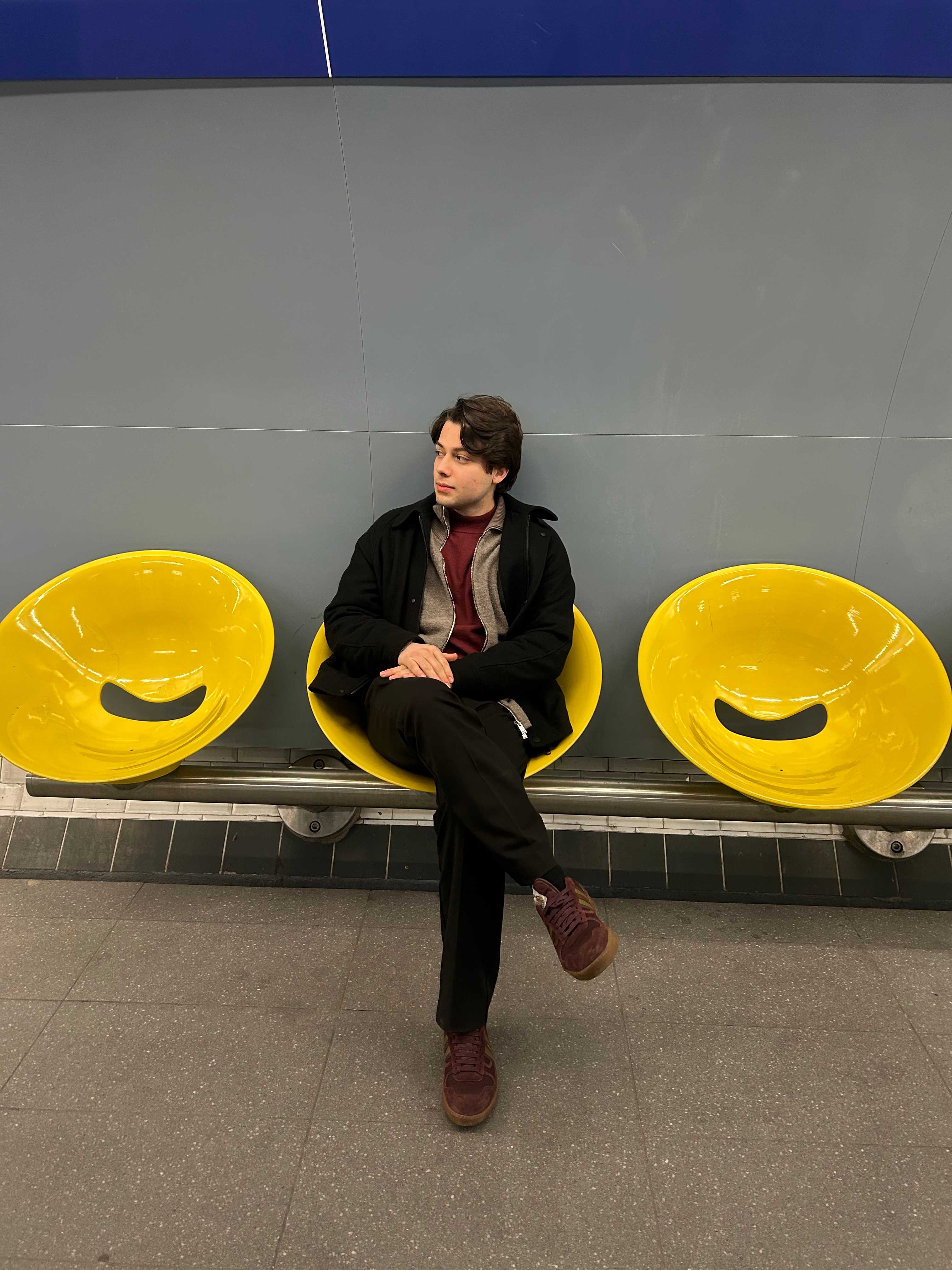 Levon sitting in a yellow chair at a subway station